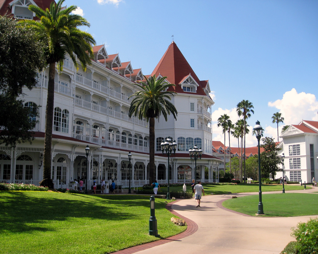 Fachada do luxuoso hotel Disney's Grand Floridian Resort & Spa com jardins e palmeiras em Orlando.